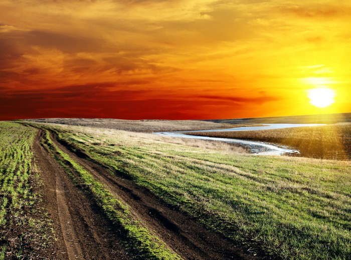 Sunset over a winding dirt road and river