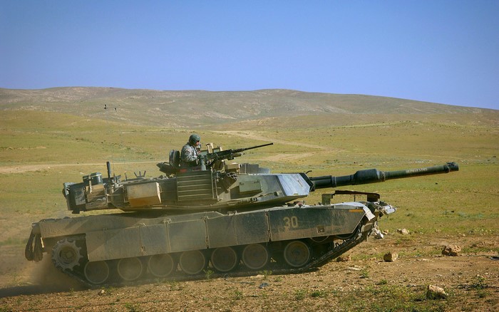 M1 Abrams tank with soldier in desert landscape