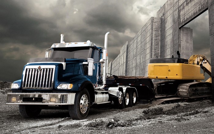 Blue International Semi-Truck with Excavator and Concrete Wall