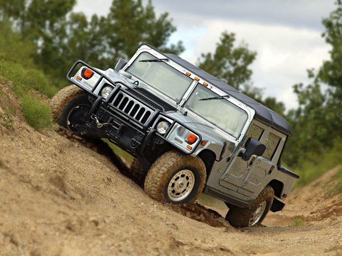 Silver Hummer H1 driving on a dirt hill