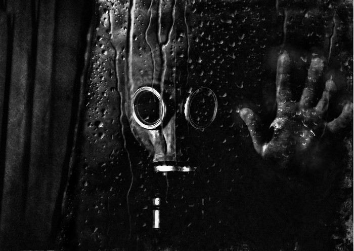 Person in gas mask behind wet glass