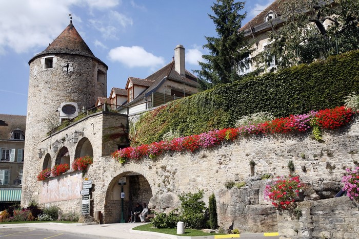 Stone tower and arched walkway with flowers in France