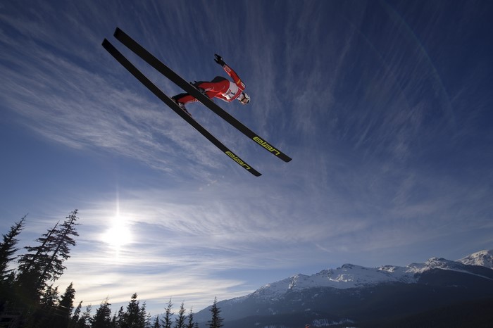 Ski jumper in mid-air against blue sky