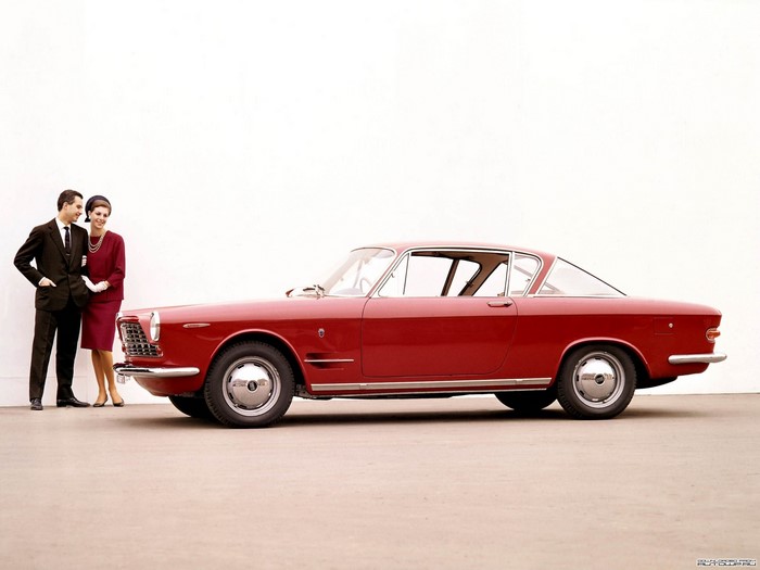 Couple posing with a red Fiat car