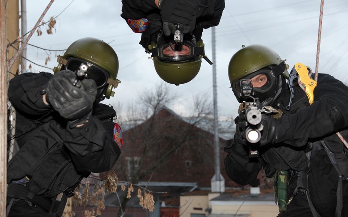 Soldiers in tactical gear rappelling with firearms