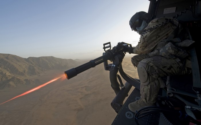 Soldier firing a minigun from a helicopter