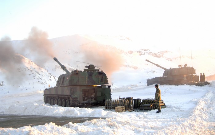 Self-propelled howitzers firing in snowy mountains
