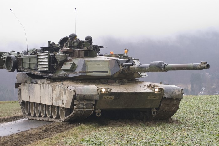 M1 Abrams tank with crew in muddy field