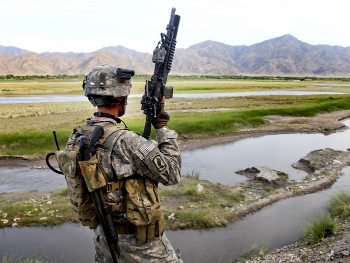 Soldier with rifle in mountainous landscape