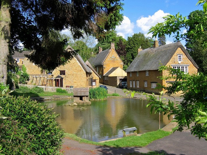 Thatched roof houses by a pond in the United Kingdom