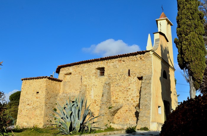 Stone church with bell tower and cypress tree