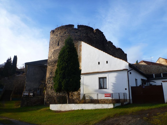 Ruins of a stone tower and white building in Czech Republic