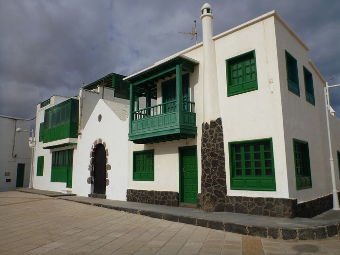 White building with green balconies in Caleta De Famara, Lanzarote, Spain