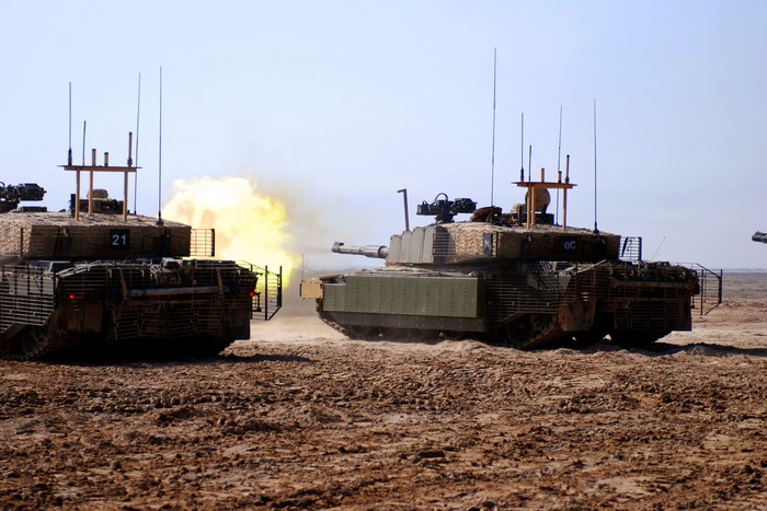 Two tanks firing in a desert landscape