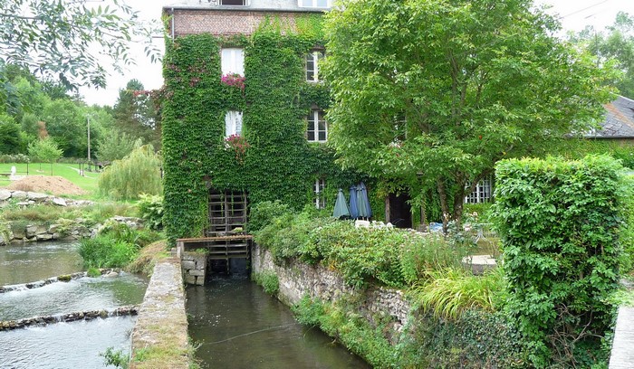 Ivy-covered mill building by a river in France