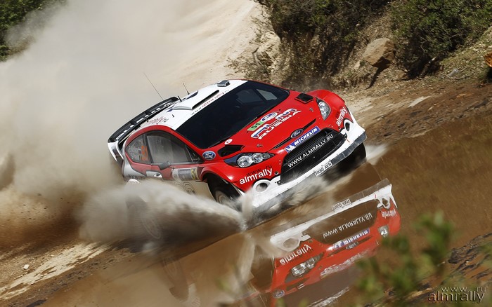 Ford Fiesta WRC car driving through water and mud