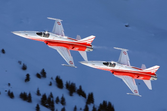 Two Swiss Air Force F-5E Tiger II jets flying over snowy mountains