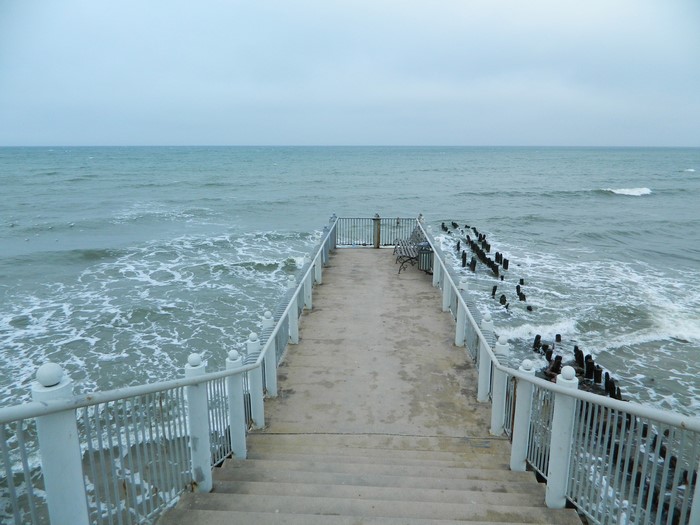 Pier extending into the ocean with wooden pilings