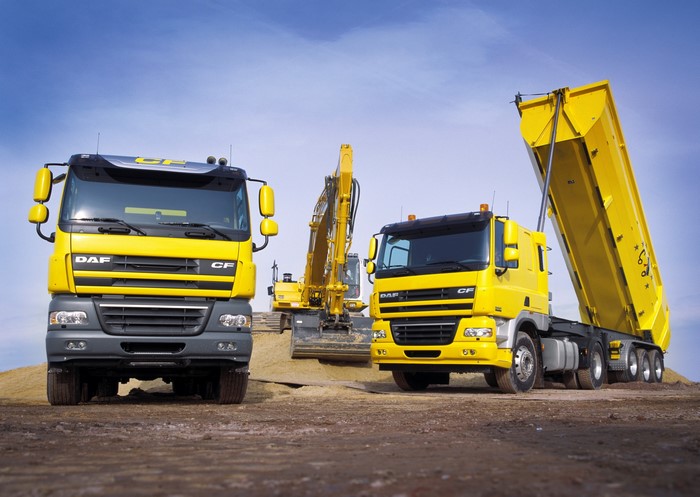 Yellow DAF CF trucks and excavator on construction site