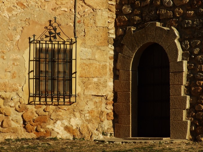 Stone wall with arched doorway and barred window