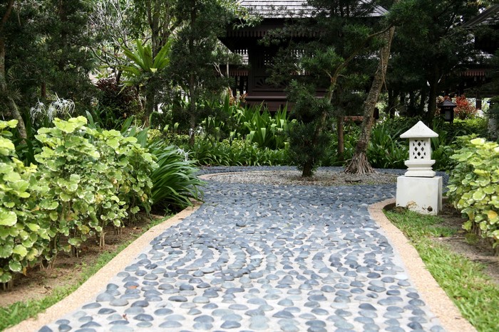 Stone pathway in a lush garden with a pagoda