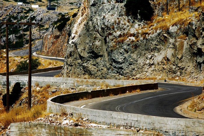 Winding mountain road with concrete barriers and power lines