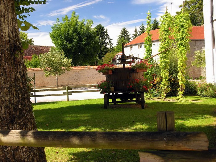 Wooden wine press with flowers in front of stone building