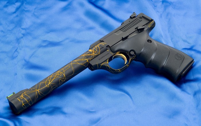 Black pistol with gold accents on blue fabric