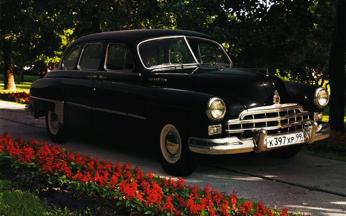 Black GAZ-21 Volga car parked by red flowers