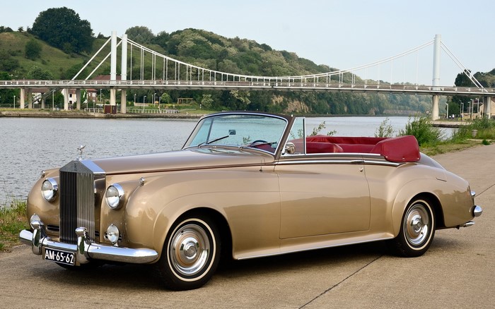 Gold Rolls-Royce convertible by a bridge