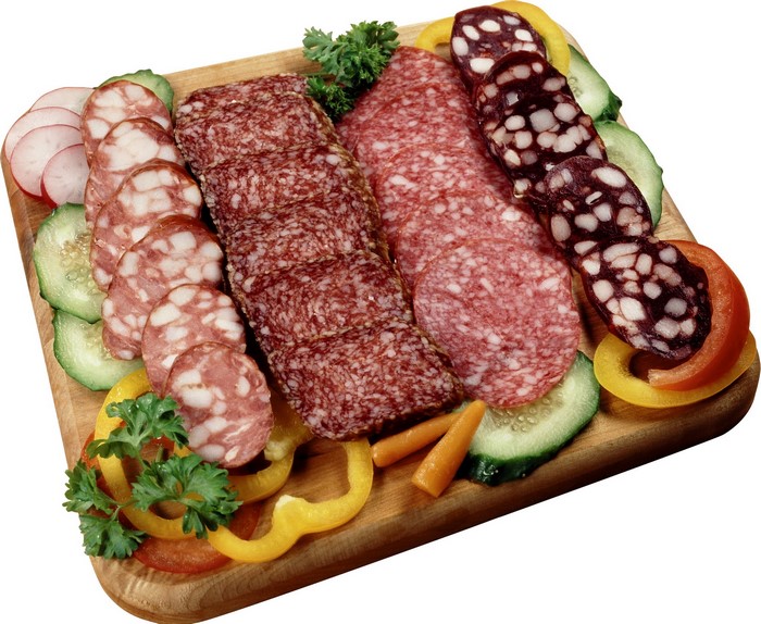 Assortment of sliced sausages and vegetables on a wooden board