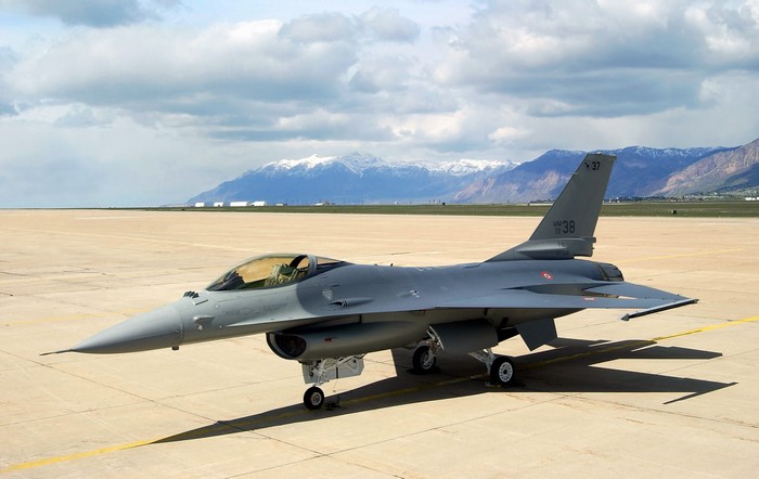 Gray F-16 Fighting Falcon on Tarmac with Mountains