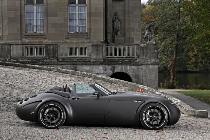 Matte black Wiesmann convertible sports car parked on cobblestone driveway
