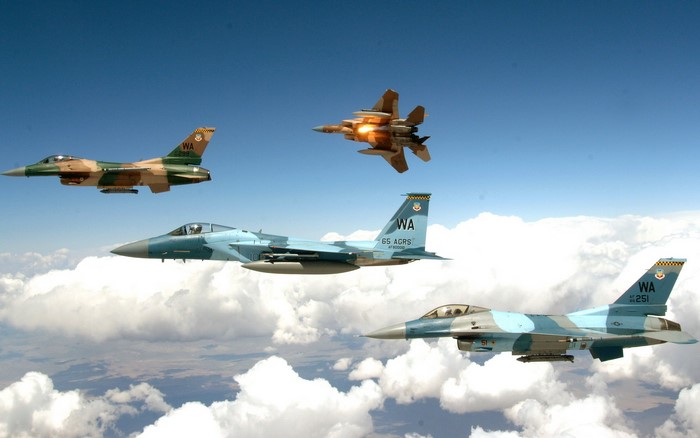 Four fighter jets flying in formation over clouds
