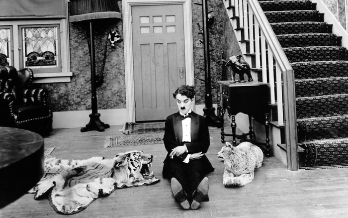 Charlie Chaplin sitting on floor with animal rugs