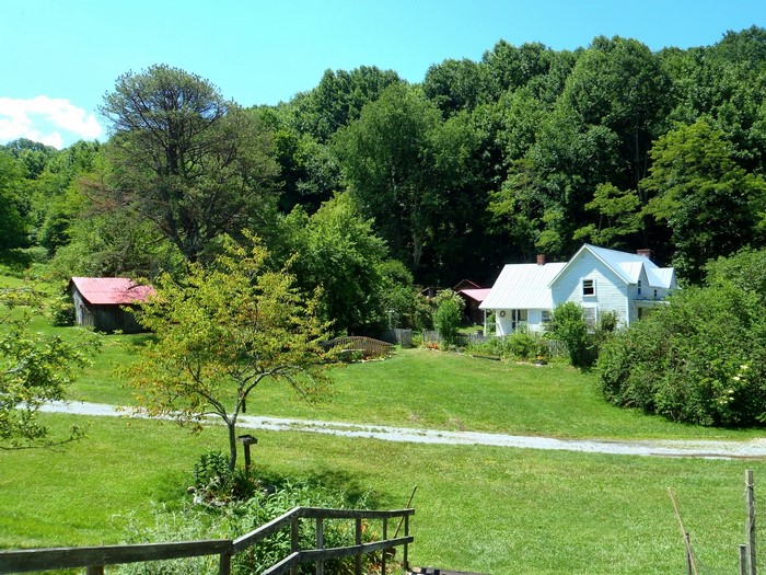 White farmhouse and barn in a wooded landscape