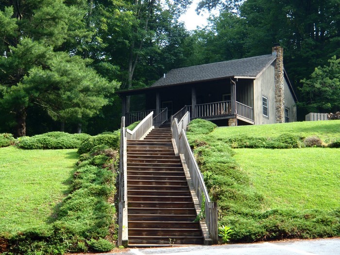 Wooden cabin with stone chimney and stairs at Roan Mountain State Park