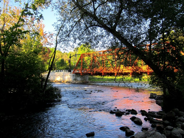 Orange bridge over Huron River with trees