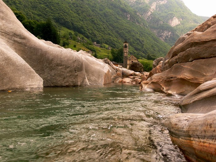 River flowing through rocky gorge with church in Switzerland
