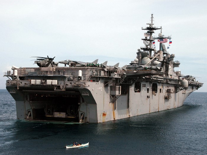 Amphibious assault ship with aircraft and a small boat
