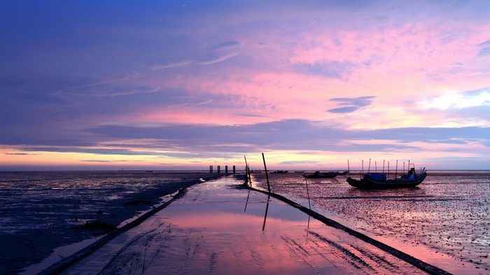 Boats on a muddy shore at sunset