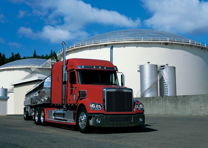 Red Freightliner truck at industrial storage tanks