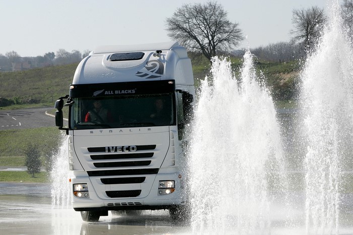 White Iveco Stralis truck driving through water