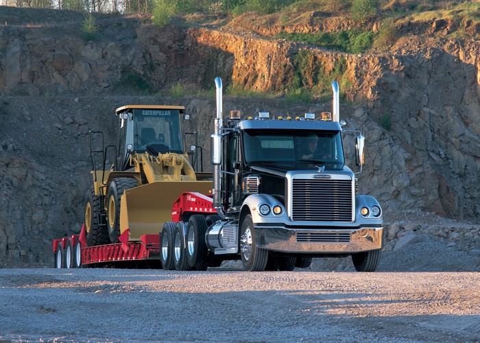 Freightliner truck carrying a Caterpillar wheel loader on a trailer