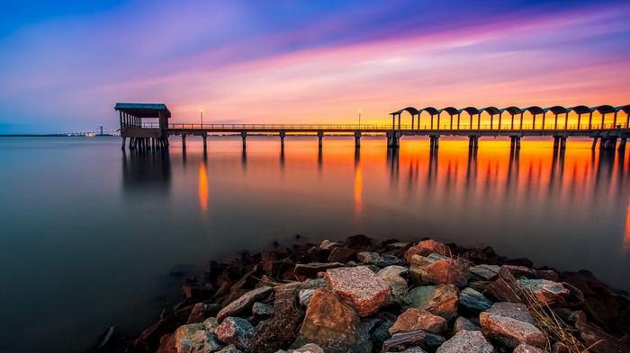 Pier over water at sunset with colorful sky