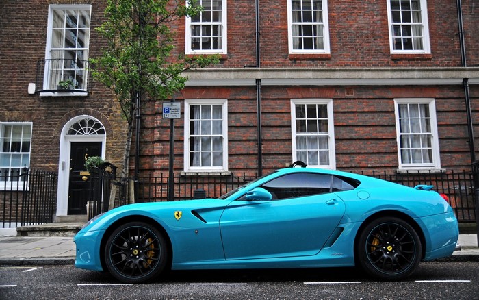 Blue Ferrari parked in front of a brick building