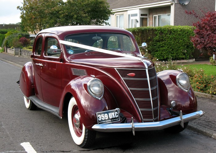 Maroon vintage car with wedding ribbon