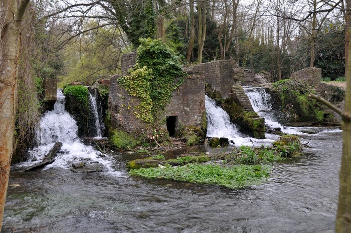 Ruined brick mill with waterfalls in a forest