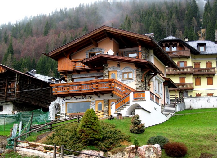 Alpine houses in Italy with forested mountain background