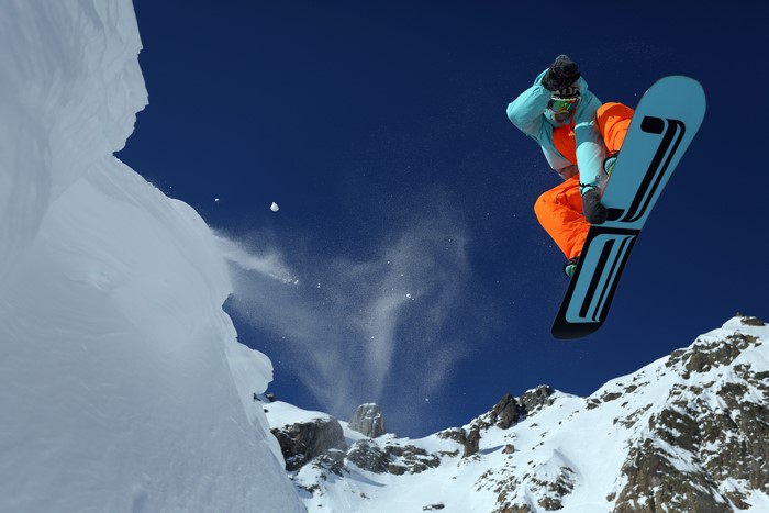 Snowboarder jumping off a snowy cliff